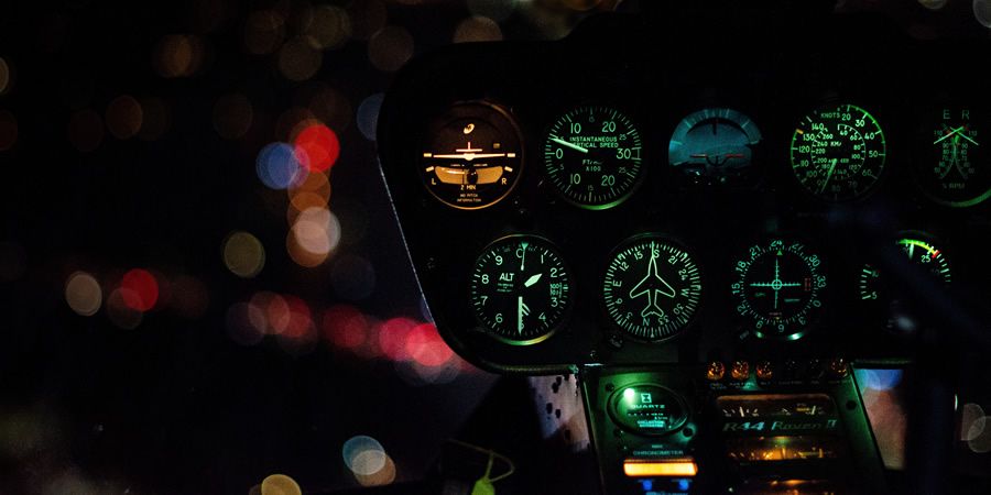 Illuminated cockpit gauges of a Robinson R44 Raven II helicopter at night.