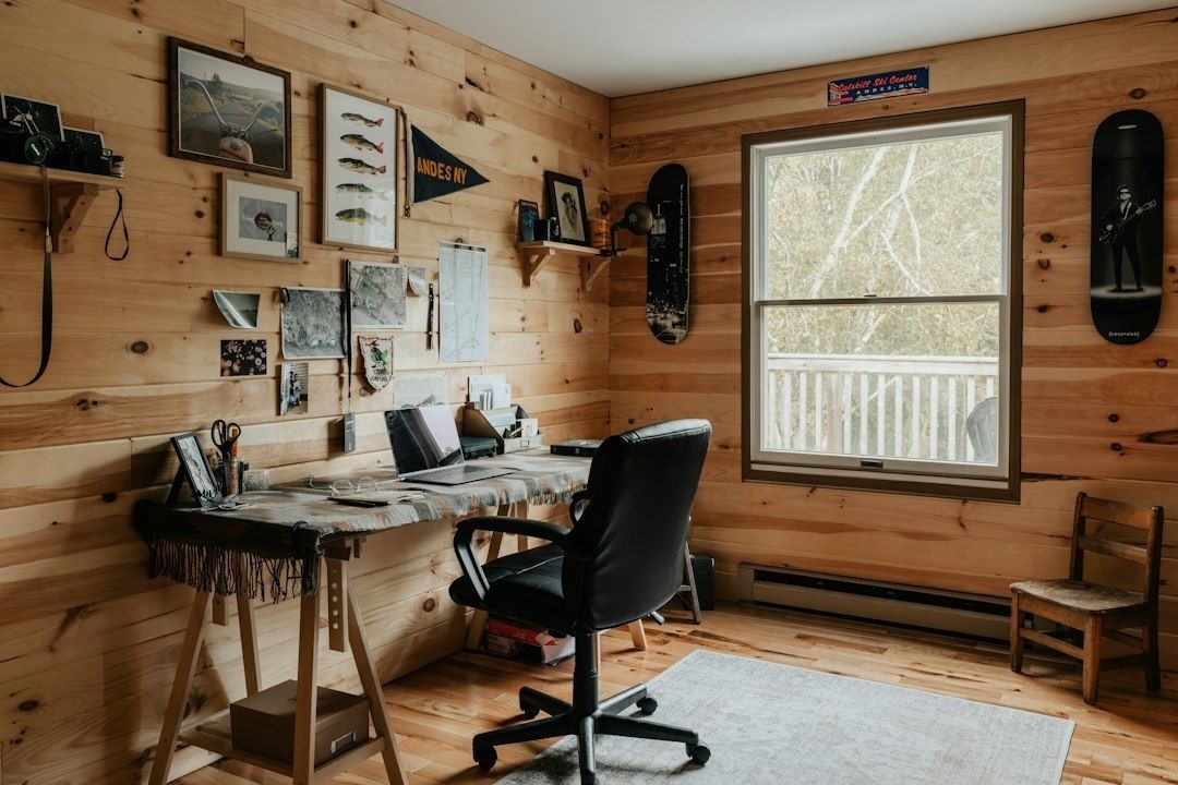 Wood-paneled home workspace with desk, office chair, maps, and boards